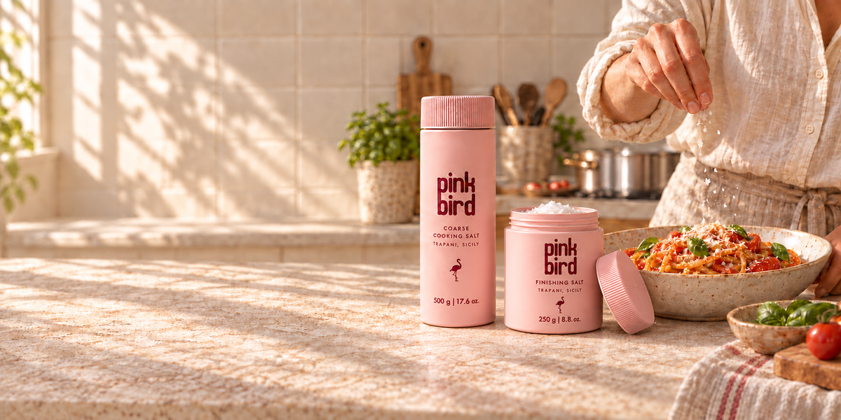 Pink Bird cooking salt and finishing salt beside a person finishing tomato pasta